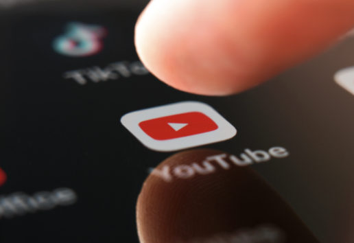 Une personne appuie sur l'icône rouge YouTube d'un smartphone.