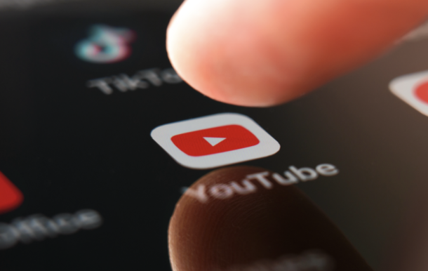 Une personne appuie sur l'icône rouge YouTube d'un smartphone.