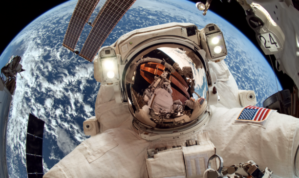 Spationaute en combinaison dans l'espace, devant la Terre, avec vue sur la station spatiale et drapeau américain.