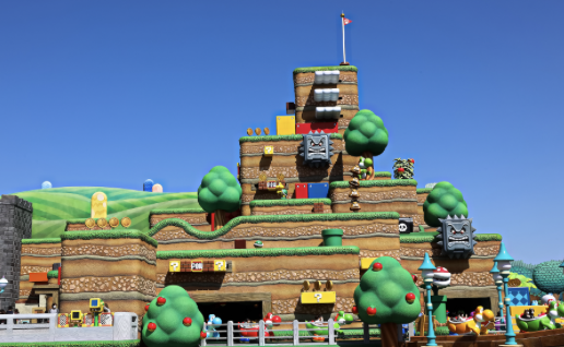 Parc à thème inspiré de jeux vidéo : château coloré avec personnages et décors animés, sous un ciel bleu clair.