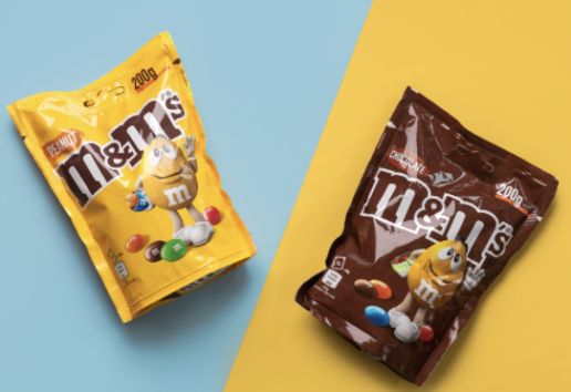 Deux sachets de bonbons M&M's : un jaune "Fruité" et un marron "Chocolat", chacun affichant 200g et un personnage M&M.