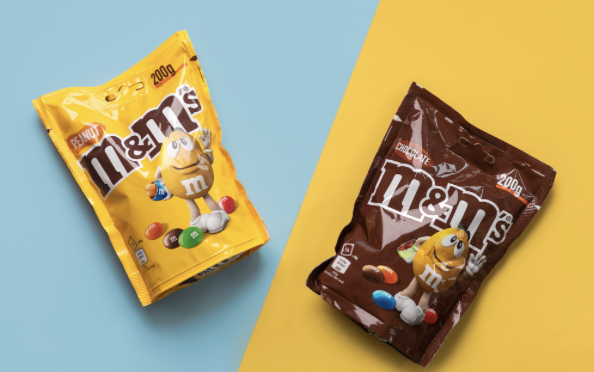 Deux sachets de bonbons M&M's : un jaune "Fruité" et un marron "Chocolat", chacun affichant 200g et un personnage M&M.