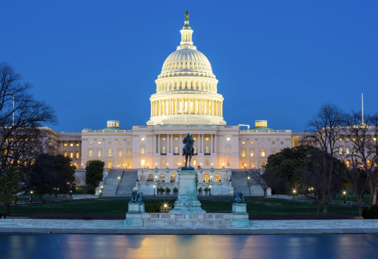 Capitole américain illuminé au crépuscule, avec son dôme brillant et une statue équestre en avant-plan, reflété dans