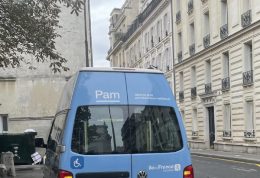 Véhicule hybride Pam accessible, stationné rue parisienne avec logo Île-de-France et mention handicap.