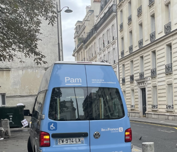Véhicule hybride Pam accessible, stationné rue parisienne avec logo Île-de-France et mention handicap.