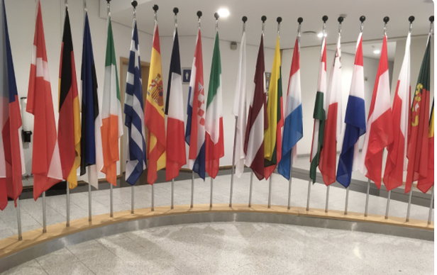 Collection de drapeaux internationaux alignés sur un présentoir circulaire en intérieur.