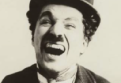 Photo en noir et blanc d'un homme souriant, portant un haut-de-forme et un costume avec cravate. Expression joyeuse et exubé