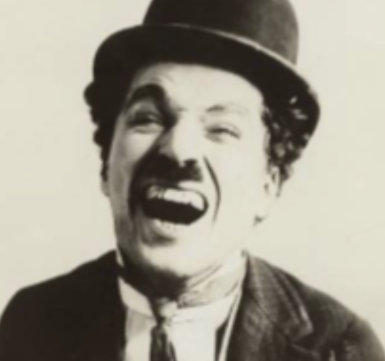 Photo en noir et blanc d'un homme souriant, portant un haut-de-forme et un costume avec cravate. Expression joyeuse et exubé