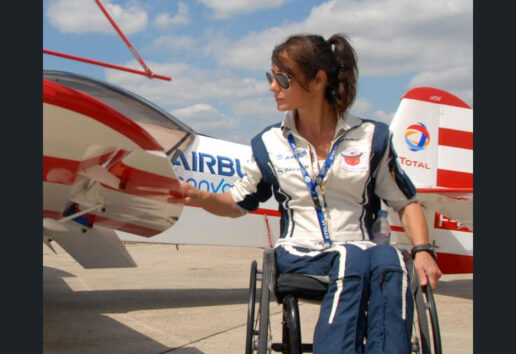 Une personne en fauteuil roulant près d'un avion Airbus, sous un ciel dégagé.