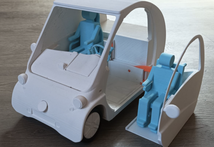Voiture miniature à hayon ouvert avec deux figurines bleues, l'une à l'intérieur, l'autre dans un compartiment arrière.